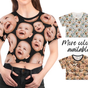 May include: A black crop top with a repeating pattern of smiling baby faces. The top is shown on a model wearing black jeans.  More colors are available.