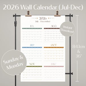 May include: A 2026 wall calendar (Jul-Dec) displayed on a black stand. The calendar is beige with monthly grids in various colors. The calendar is 84.1cm tall and includes the text "Sunday & Monday" and "Instant Download".