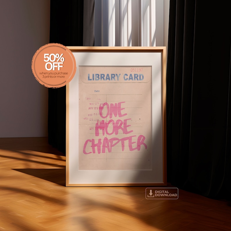 K&ouml;nnte beinhalten: Ein gerahmter Druck mit einem Vintage-Bibliothekskartendesign. Der Text "ONE MORE CHAPTER" ist in Pink auf die Karte geschrieben. Der Druck ist in einem hellen Holzrahmen und liegt auf einem Holzboden.