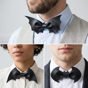 May include: A collection of three black bow ties made of a textured material, each featuring a distinct bat-wing shape. The bow ties are worn around the collar of a light-colored shirt, showcasing different wing designs including pointed and rounded edges.