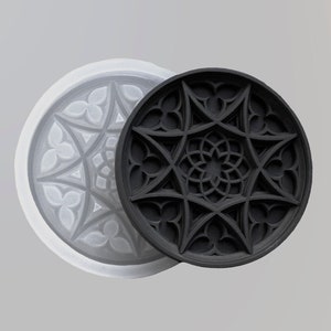 Puede incluir: Un molde de silicona blanco y negro para hacer posavasos de resina. El molde presenta un diseño geométrico detallado inspirado en las vidrieras.