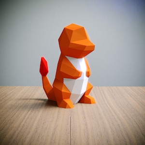 May include: Orange and white origami papercraft of a Pokemon character, Charmeleon. The figure has a red tail and is standing on a wooden surface.