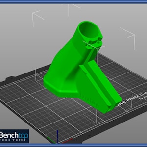 May include: A green 3D printed object with a cylindrical top and a flat base. The object is printed on a black and white grid surface. The text "ORIGINAL PRUSA I3 MK3 by Josef Prusa" is visible on the surface.