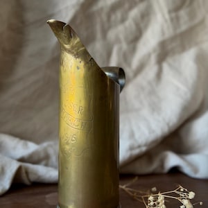 May include: A set of three ceramic mugs with a speckled, cream-colored glaze. Each mug features a different hand-painted floral design in shades of blue, green, and yellow. The mugs have a simple, rounded shape.