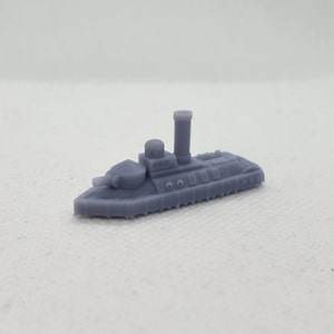 May include: A gray 3D printed model of a small, historic ironclad warship with a single turret and a tall smokestack.