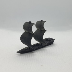 Puede incluir: Un barco en miniatura negro con dos velas. El barco está hecho de plástico y tiene un diseño detallado.