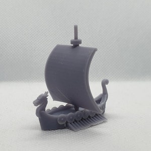 Könnte beinhalten: Ein graues 3D-gedrucktes Modell eines Wikinger-Langschiffs mit einem Drachenkopf am Bug, einem einzigen Segel und einer Reihe von Schilden an der Seite.