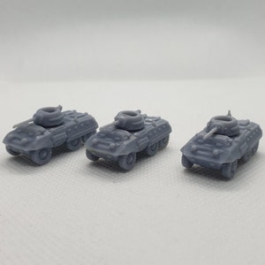May include: Three grey, miniature, plastic model armoured cars with raised guns. The cars are facing forward and are arranged in a row.