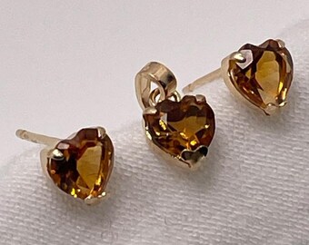 Puede incluir: Un conjunto de pendientes y un colgante de corazón de oro con piedras preciosas de topacio marrón.