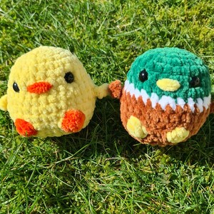 Handmade crochet duck plush with yellow chick plush on grass