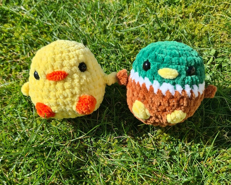 Handmade crochet duck plush with yellow chick plush on grass