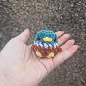 Tiny mallard duck plush sitting in palm showing scale of miniature crochet toy