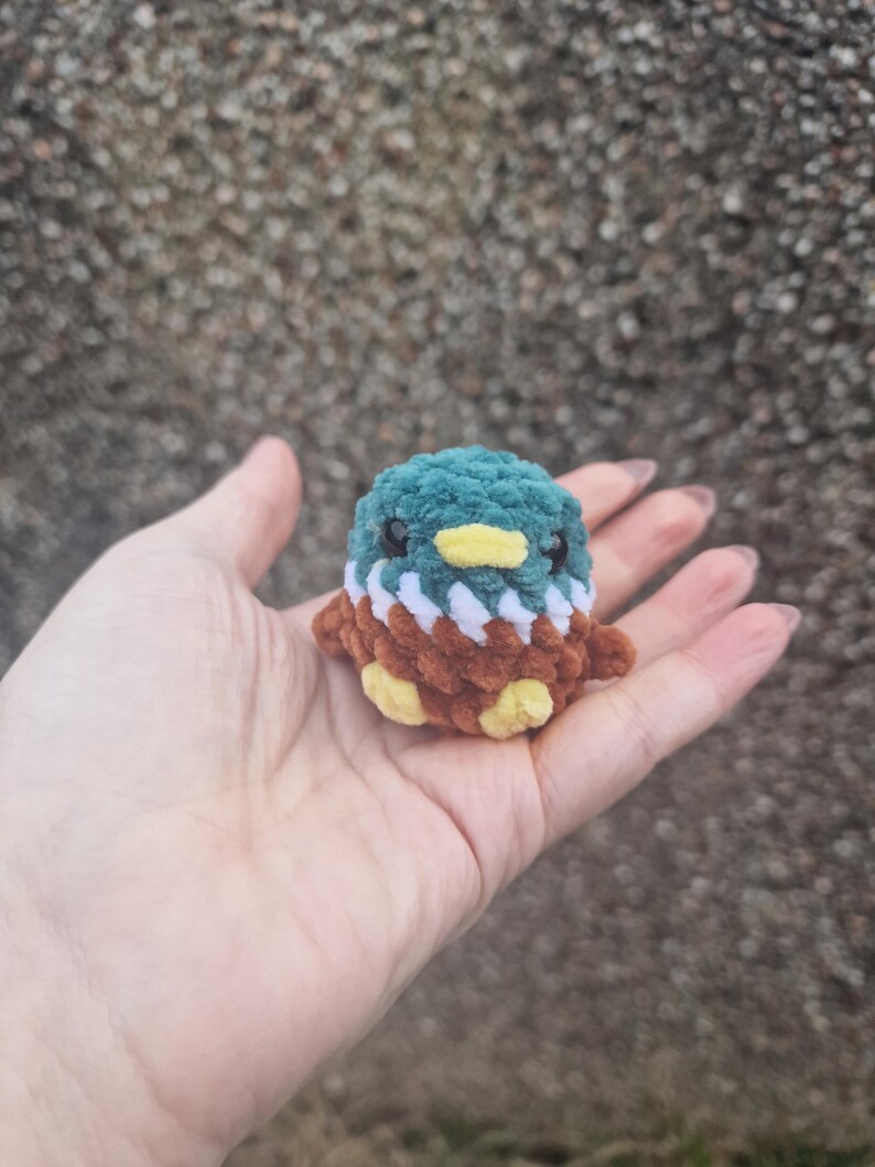 Tiny mallard duck plush sitting in palm showing scale of miniature crochet toy