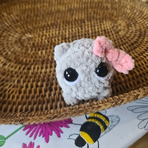 Viral sad hamster crochet cuddly toy made in fluffy grey yarn with large safety eyes and a pink bow