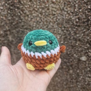 Tiny mallard duck plush sitting in a hand showing the small 7cm size