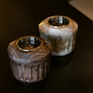 May include: Two wooden incense burners with brass accents. One is brown with a wood grain pattern and the other is white with a marbled pattern.