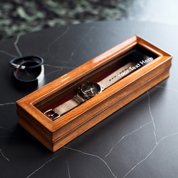 A glass-topped walnut watch box with custom engraving is the kind of handsome desk object that makes a watch collection feel intentional and curated.