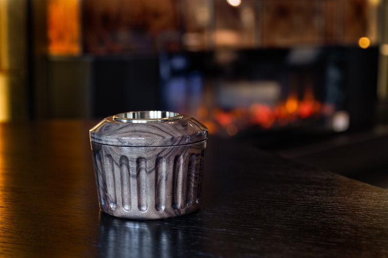 May include: A dark wood and brass incense burner with a fluted design. The burner is sitting on a dark wood table.