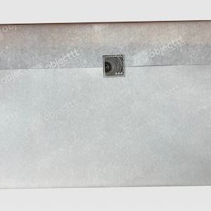 May include: A white envelope with a black and white circular design stamp in the center.