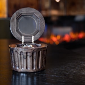 May include: A dark wood watch box with a hinged lid, open to reveal a silver watch inside.