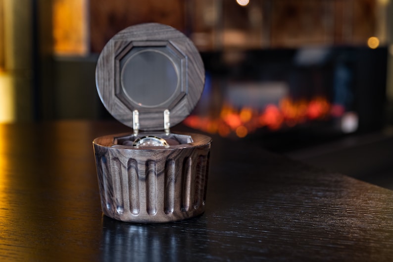 May include: A dark wood watch box with a hinged lid, open to reveal a silver watch inside.