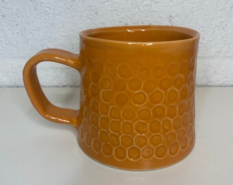 Large handmade ceramic pottery mug in orange with dimples/spotted design.