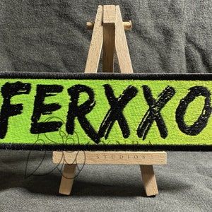 May include: A green and black embroidered patch with the word "FERXXO" written in black on a bright green background.