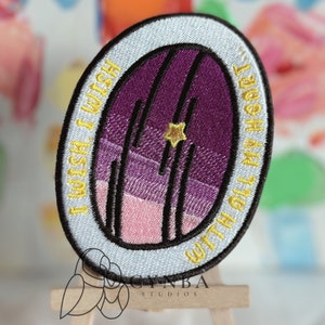 May include: An embroidered iron-on patch with a purple and pink gradient design of a closed door with a star above it. The text around the door reads "With all my heart I wish I wish I wish".