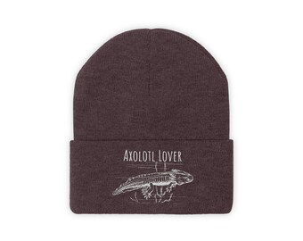 May include: A dark brown beanie with the text "AXOLOTL LOVER" above a white illustration of an axolotl. The axolotl is drawn in a detailed, scientific style, with visible gills and limbs. The beanie is a classic, cuffed style.