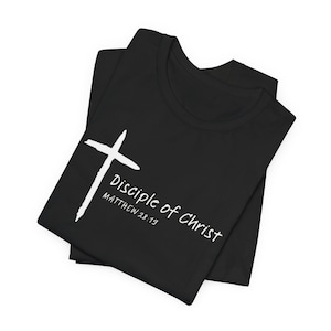 May include: Black t-shirt with a white cross and the text "Disciple of Christ" and "Matthew 28:19". The t-shirt is folded and appears to be made of a soft material.