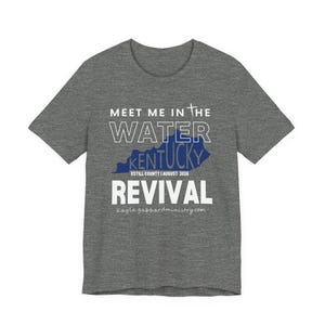 May include: A heather grey short-sleeve t-shirt featuring a blue silhouette of Kentucky with the text MEET ME IN THE WATER, KENTUCKY, ESTILL COUNTY AUGUST 2026, REVIVAL, and kaylagabbardministry.com printed in white and blue across the chest.