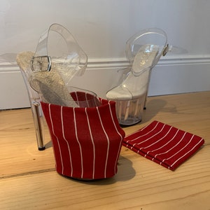Könnte beinhalten: Transparente Plateau-High Heels mit Knöchelriemen und einer rot-weiß gestreiften Stoffhülle. Ein passendes Stoffquadrat liegt neben den Absätzen. Die Absätze stehen auf einer hellen Holzoberfläche.