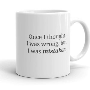Peut inclure: Une tasse à café en céramique blanche avec du texte noir qui dit "Once I thought I was wrong, but I was mistaken."