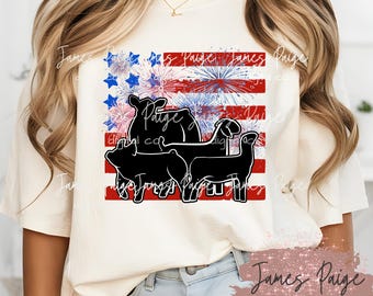 May include: Cream-colored t-shirt featuring a graphic of farm animals in silhouette against a stylized American flag design. The flag incorporates red and white stripes, blue stars, and fireworks. The text "James Paige digital co" is also visible.