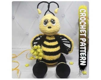 May include: A crocheted bee toy with black and yellow stripes, black wings, and a yellow flower bouquet. The bee has black eyes and a smiling mouth. The text "CROCHET PATTERN" is written vertically on the right side of the image.
