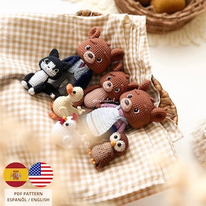 Puede incluir: Una colección de juguetes de animales de ganchillo hechos a mano, incluyendo osos, un gato, un ratón, una gallina y un búho, dispuestos en una cesta de mimbre. Los juguetes son de varios colores, siendo el marrón, blanco y negro los más prominentes. La imagen también incluye el texto "PDF Pattern Español / English".