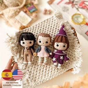 Puede incluir: Tres muñecas de ganchillo, cada una con atuendos y peinados únicos, se exhiben sobre una superficie tejida. Las muñecas incluyen un personaje con un mono marrón, una con un vestido rosa y chaqueta azul, y otra con un atuendo morado. También se ve el texto "PDF Pattern Español / English."