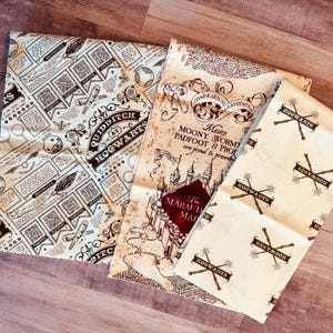 Op de afbeelding: Drie stoffen met Harry Potter-thema's. Eén toont een kaart met tekst, een andere heeft een Quidditch at Hogwarts-patroon, en de derde toont herhaalde Hogwarts-logo's met gekruiste toverstokken. De stoffen zijn in crème, bruin en rood.