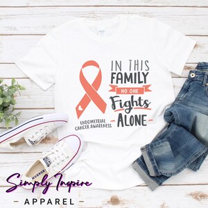 Camisa de apoio \ Camisa de conscientização sobre câncer endometrial \ Nesta família ninguém luta sozinho \ Camisa de luta contra o câncer \ Moletons unissex