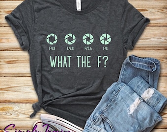 Może przedstawiać: Szary t-shirt z nadrukiem czterech ustawień przysłony aparatu i tekstem "WHAT THE F?" w jasnozielonym kolorze.