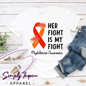 May include: White t-shirt with an orange and red ribbon, flowers, and the text "Her Fight Is My Fight Myelofibrosis Awareness".