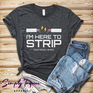 May include: A dark gray t-shirt with a graphic of electrical wires being stripped. The text on the shirt reads "I'm here to strip electrical wires".