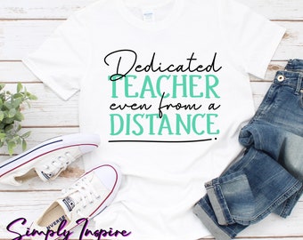 Może przedstawiać: Biała koszulka z czarnym napisem "Dedicated Teacher even from a DISTANCE". Tekst jest napisany kursywą. Koszulka jest złożona i leży na drewnianej powierzchni z parą białych butów sportowych i niebieskimi dżinsami.