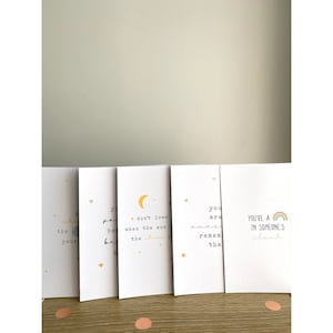 May include: Five white cards with different inspirational quotes and illustrations. The quotes include "You are amazing, remember that", "You're a in someone's cloud", "Don't lose your peace when the sun goes down", "Shine like the stars", and "You are beautiful & brave".
