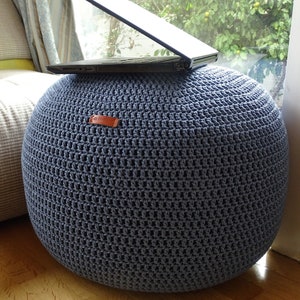 Könnte beinhalten: Ein blauer gehäkelter Hocker mit einem Laptop darauf. Der Hocker steht auf einem Holzboden.