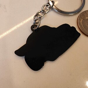 May include: A black metal keychain with a car silhouette attached to a silver chain and ring.