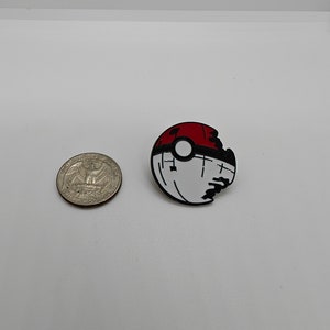 May include: A red and white Pokeball pin with a bite taken out of it. The pin is made of metal and has a black outline.