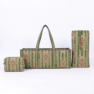 May include: A set of three quilted fabric items in a sage green and dark green striped pattern featuring a repeating tiger print. The set includes a small rectangular zippered pouch, a long open tote bag with two handles, and a tall drawstring bag.