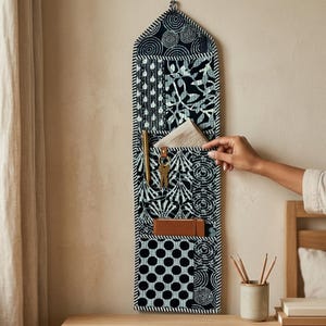 Zwarte patchwork gewatteerde wandorganizer, handgemaakte katoenen opbergvakken, patroonrijke organizer voor thuis en kantoor.