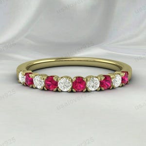 以下が含まれることがあります： 交互に赤と白の丸い宝石が並んだ金のバンドリング。リングは、小さな丸い赤い宝石の列と、小さな丸い白い宝石の列で飾られています。